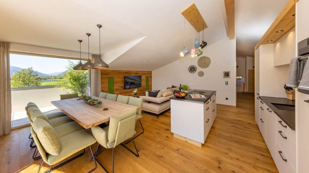 Open-plan living area in the penthouse with kitchen, dining table, sofa and smart TV